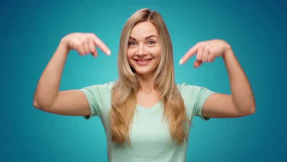 Young Woman Pointing Fingers Down Showing Copy Space Against Blue Background