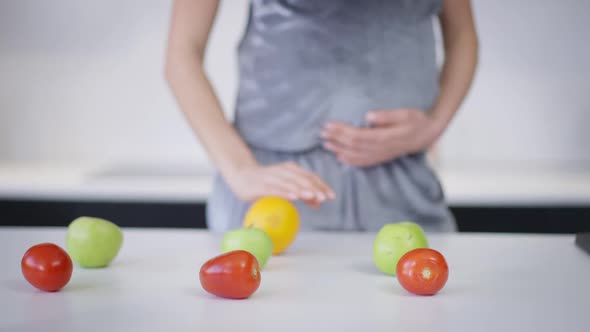Healthful Vegetables and Fruits Lying on Countertop with Unrecognizable Pregnant Caucasian Woman