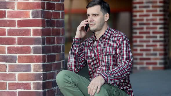 Urban portrait of handsome millenial man using mobile phone