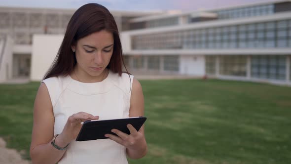 Focused Young Redhead Girl Using Modern Tablet Outdoor