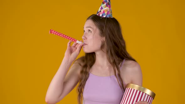 Portrait of a young girl in party con with a gift in her hands celebrating birthday.