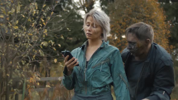 Clumsy Zombie Thief Trying To Take Smartphone Away From y Woman Walking Outdoors