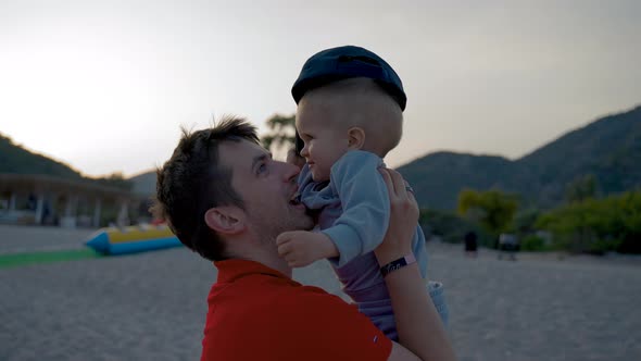 Father Holds Toddler Son Spending Time on Beach at Sunset
