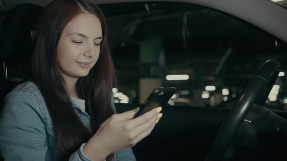 Woman Uses an Application on His Phone While Sitting in the Car in the Parking Lot