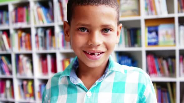 Portrait of schoolboy smiling in library at school