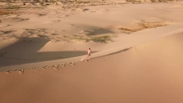 Aerial View of Man Running Along Large Sand Dunes.