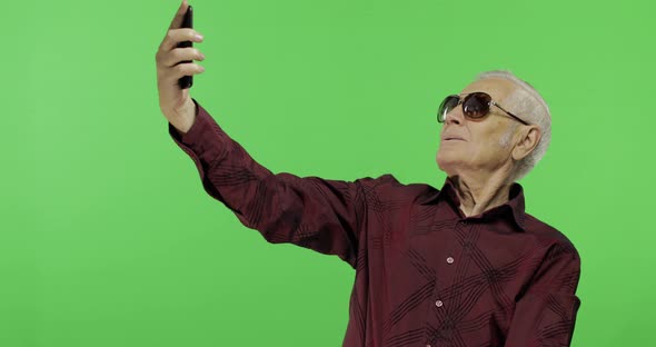 Senior Man Tourist in Sunglasses Make a Photo on a Smartphone. Selfie