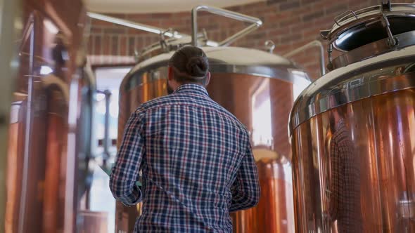 Serious Professional Brewer with Tablet Turning Checking Highquality Beer Production Indoors