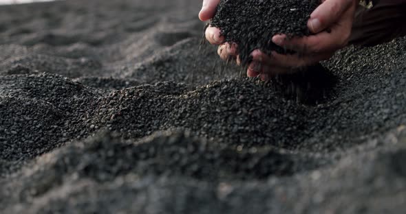 Slow Motion of Men's Hands Take the Black Volcanic Sand, Pouring Through the Fingers at Reynisfjara