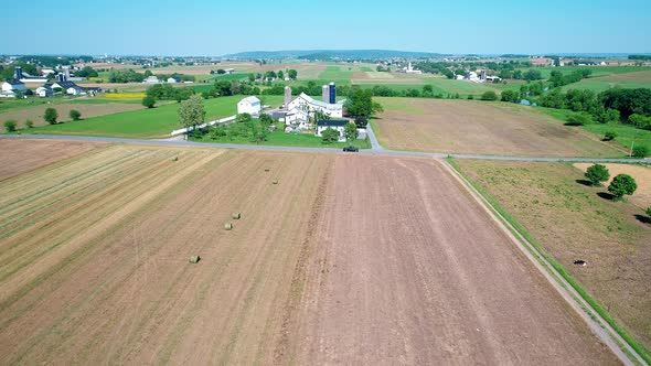 Amish Farm Worker Harvesting the Fields with old and New Equipment