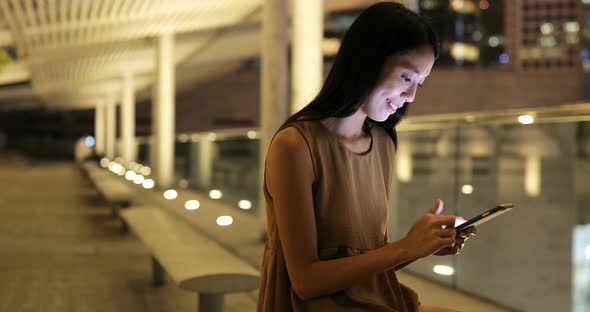 Woman looking at mobile phone in city at night 