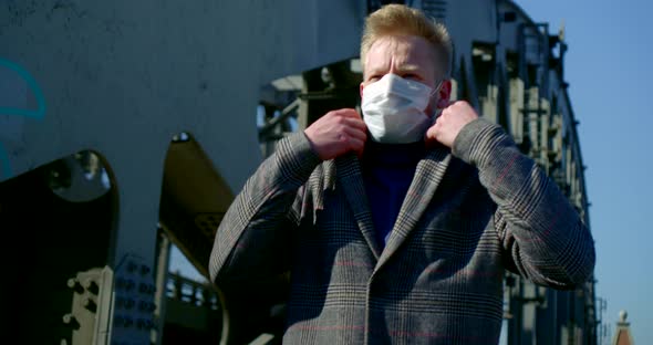 Portrait of a Man on a City Street. He Puts a Disposable Mask on His Face, Walks Along the Bridge