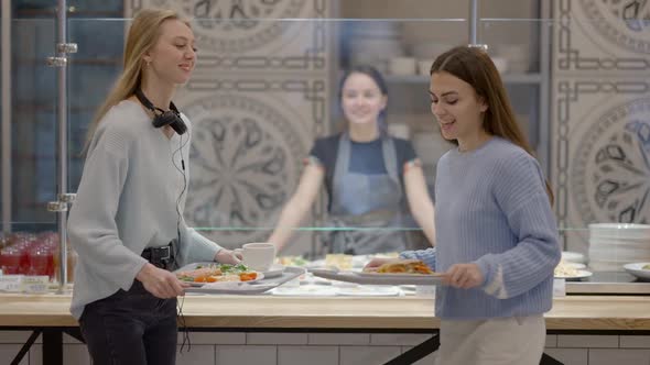 Positive Female Friends Taking Trays with Food in Selfservice Restaurant and Leaving in Slow Motion