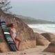 Woman Poses with Surfboard in Case Leaning Against Rock - VideoHive Item for Sale