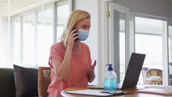Woman wearing face mask talking on smartphone at home
