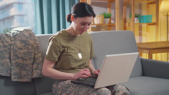 Young Smiling Military Woman Sits at Her Laptop