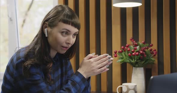 Portrait of a Young Girl in Headphones Talking in Front of a Laptop Screen