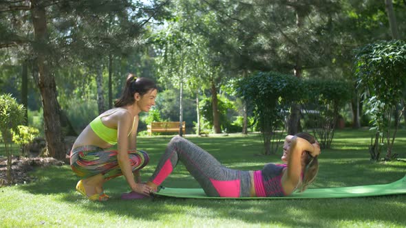 Woman with Assistance of Female Friend Doing Sit-ups