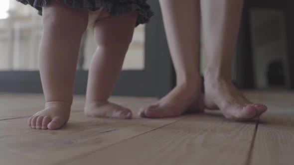 Feet of a Young Woman and Her Baby Standing on the Floor at Home