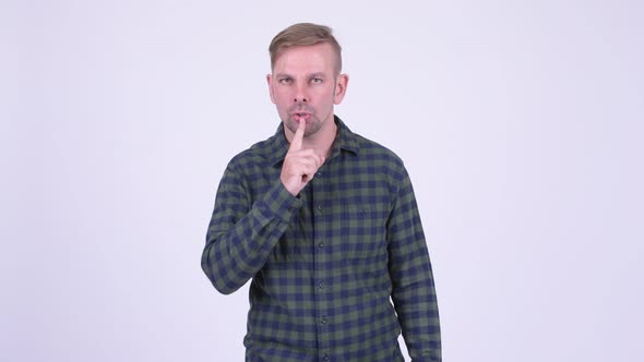 Portrait of Happy Blonde Hipster Man with Finger on Lips