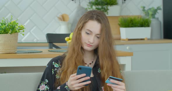 Woman Making a Payment Using Credit Card and Smartphone in Modern Contemporary House / Electronic