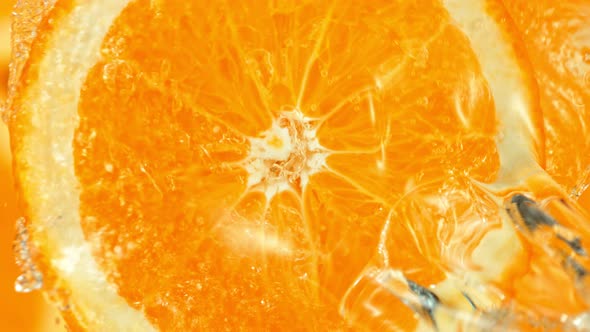 Super Slow Motion Shot of Splashing Water on Rotating Orange Slice at 1000Fps