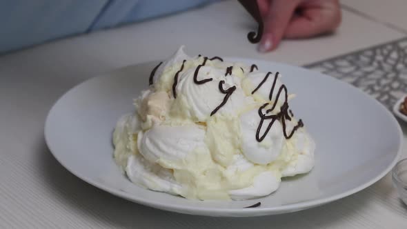 A Woman Prepares A Cake Count Ruins From Meringue. Decorate The Cake With Liquid Chocolate.