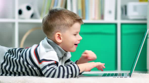 A Child Boy is Surfing the Internet on His Laptop