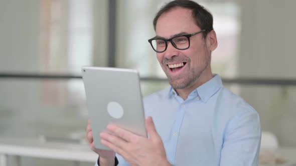 Middle Aged Man Celebrating on Tablet in Office