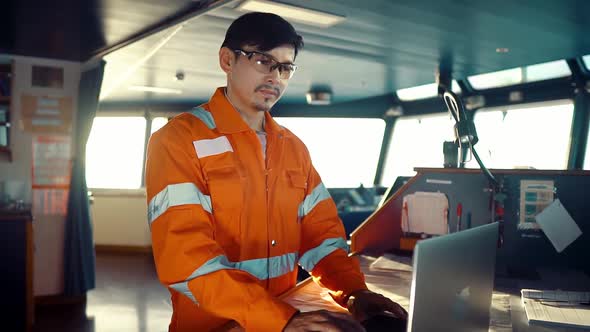 Filipino Deck Officer on Bridge of Vessel or Ship. He Is Using Laptop, Electronic Paperwork at Sea