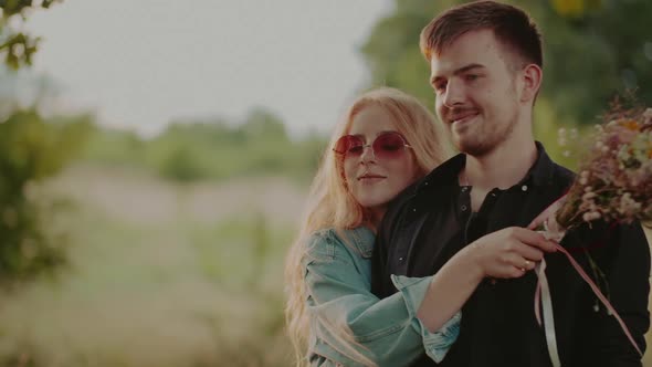 Woman Supporting Young Man Outdoors at Sunset