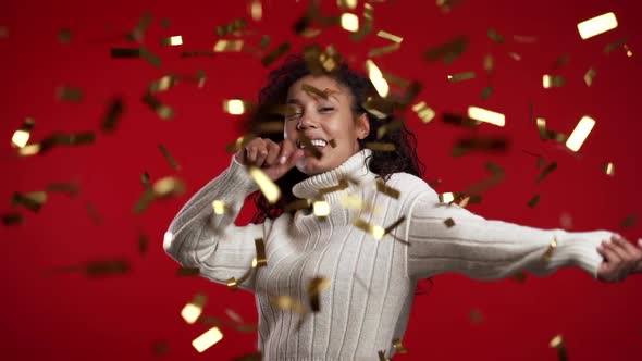 Excited African Woman Dancing, Having Fun, Over Confetti Rain in Red Studio