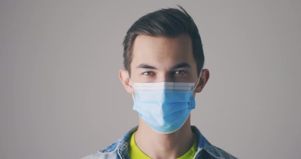 Young Male Removes the Face Protective Mask and Looking at the Camera