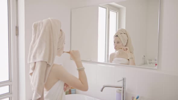 Teenage girl brushing her teeth in the bathroom in the morning