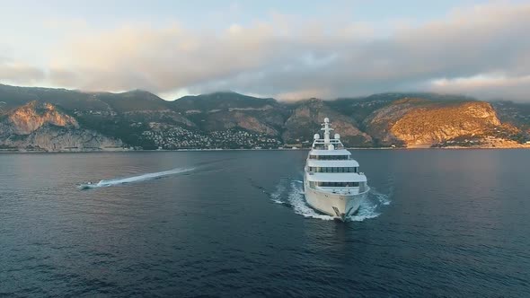 Private luxury yacht and small boat underway, front view. Super yacht