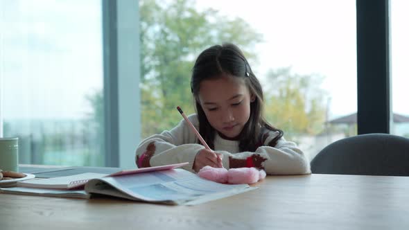 Positive Asian girl writing in notepad