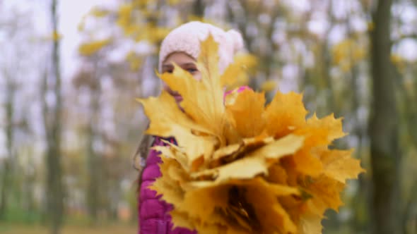 Smiling Girl Showing Bouguet of Autumn Leaves