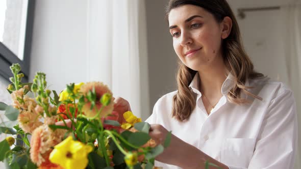 Happy Woman Arranging Flowers in Vase at Home