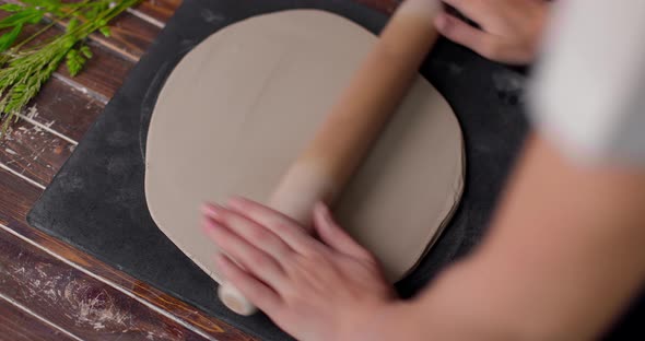 Female Hands Flatting Piece of Clay Lying on Fabric Using Wooden Rolling Pin in Ceramic Studio