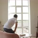 A man in spacious room gets up from the sofa and goes to think to the big window - VideoHive Item for Sale