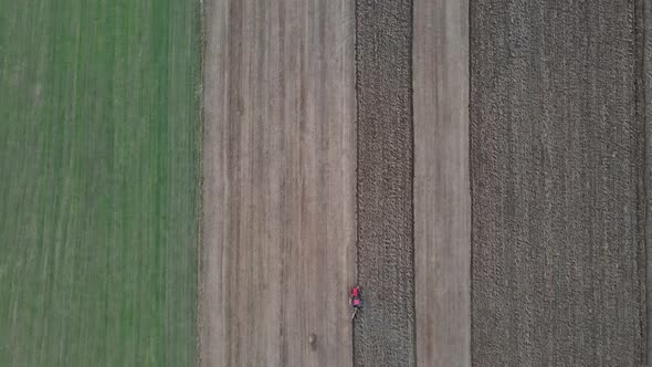 Aerial View of Tractor Plows the Field in the Evening at Sunset.