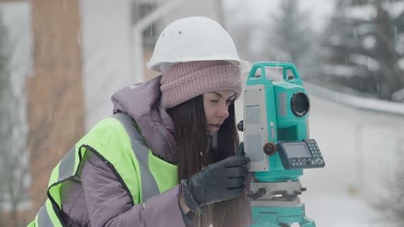 Concentrated Woman in Hard Hat Using Industrial Equipment Outdoors in Winter