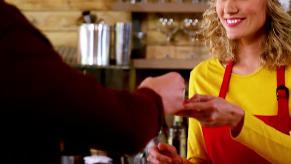 Waitress serving a cup of tea to customer at counter in caf������������