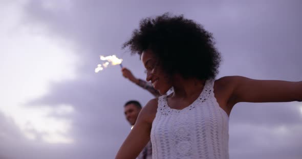 Couple dancing with sparklers on beach at dusk 4k