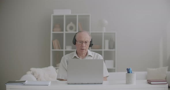 Aged Male Teacher Is Giving Lectures Online, Staying Home, Using Laptop with Internet Connection and