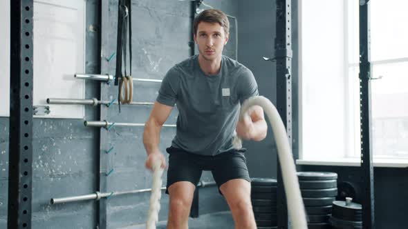 Portrait of Handsome Sportsman Training in Crossfit Gym Battling Ropes Alone