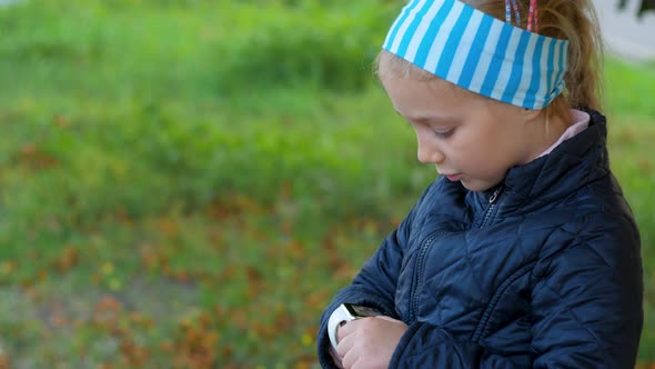 Child using smartwatch outdoor in autumn park Kid talking on vdeo call on the smartphone