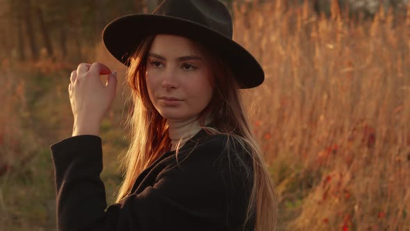Beautiful Girl in a Hat on a Sunset Background