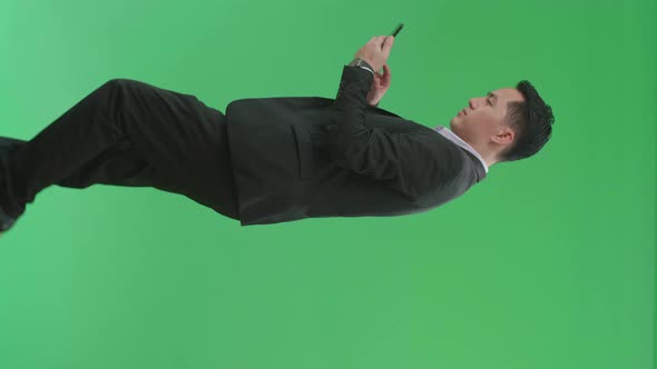 Side View Of Asian Business Man Use Mobile Phone While Walking On Green Screen Chroma Key