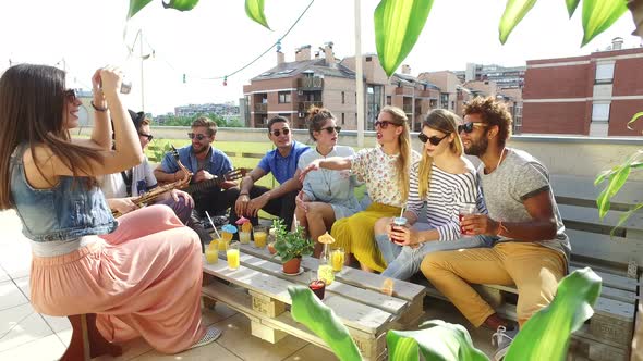 Beautiful girl taking photos of friends at party on a rooftop terrace